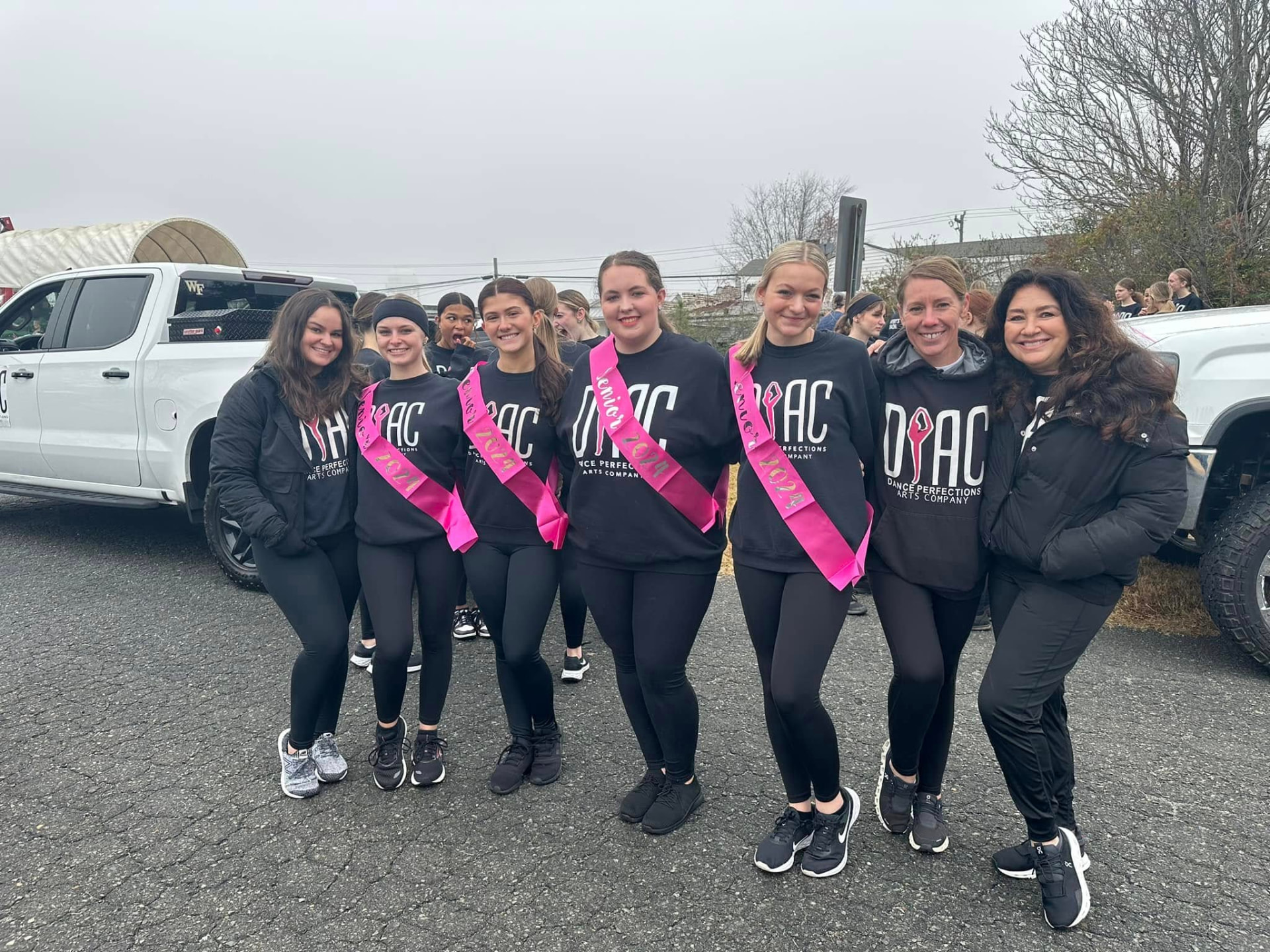 Senior dancers in sashes celebrating with their instructors
