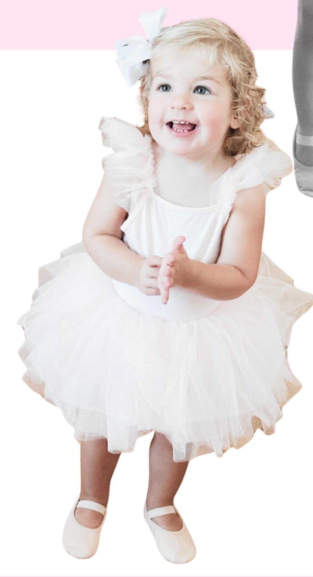 Toddler in a white tutu smiling during a TuTu Tots ballet class